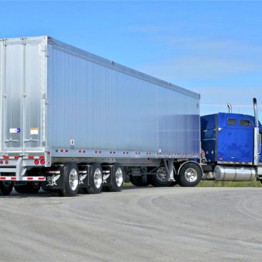 Metallic recycling truck being pulled by a blue tractor